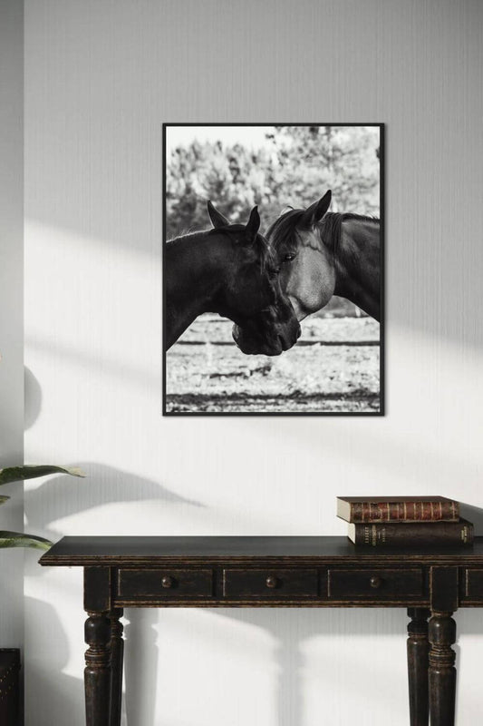 Photographie de chevaux en noir et blanc encadrée, accrochée au‑dessus d’une console en bois sombre dans un intérieur minimaliste.
