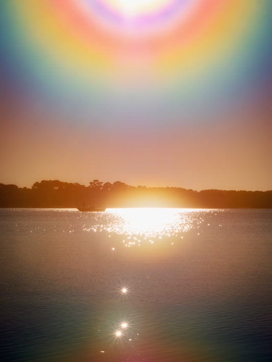 Photographie fine art de Maxime Guengant : un halo lumineux irisé au-dessus du lac de Sanguinet au coucher du soleil. Une scène contemplative et céleste capturant la poésie de la lumière.