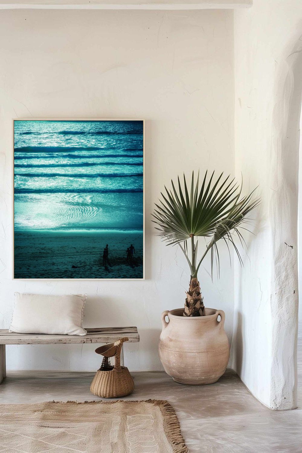 Tirage Azur Dreams encadré, vagues turquoise et silhouettes, présenté dans un intérieur naturel avec banc en bois et plante tropicale.

