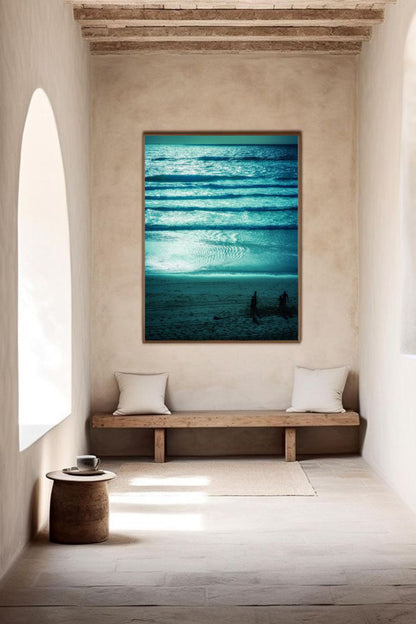 Tirage Azur Dreams encadré, vagues turquoise et silhouettes jouant sur le sable, présenté dans un intérieur lumineux et minimaliste.
