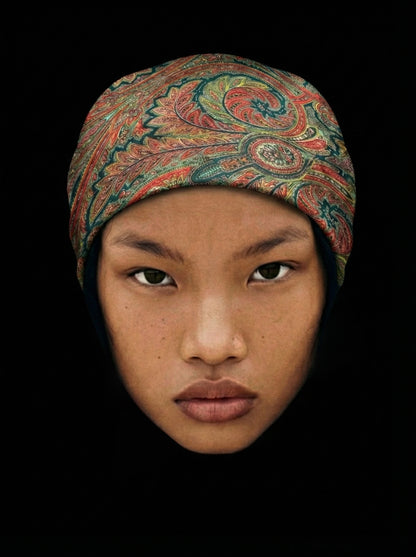 Portrait d’une femme portant un bandana Héritage motif traditionnel sur fond noir.