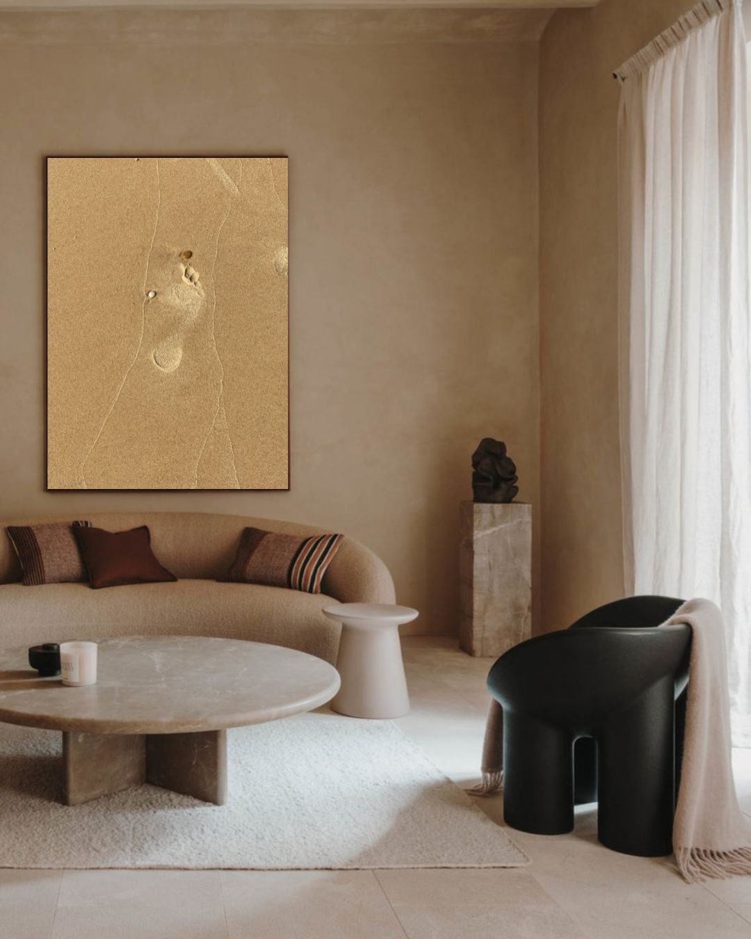 Photographie The Human Step encadrée dans un salon minimaliste beige avec canapé arrondi et table en pierre.