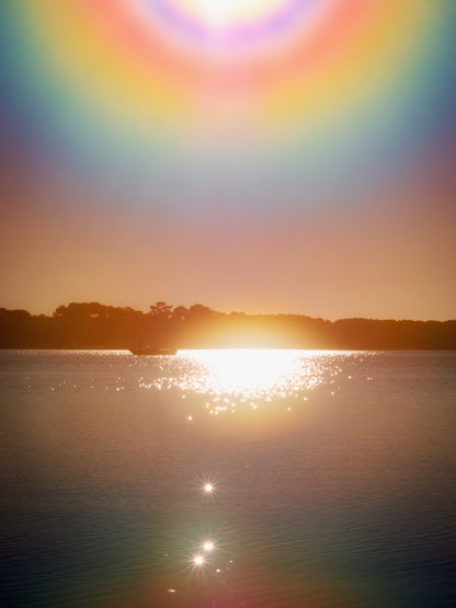 Photographie fine art de Maxime Guengant : un halo lumineux irisé au-dessus du lac de Sanguinet au coucher du soleil. Une scène contemplative et céleste capturant la poésie de la lumière.