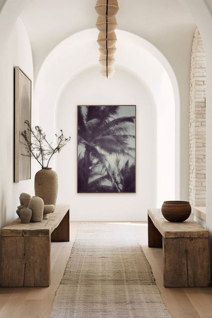  Tirage d’art “Tropical Breath” de Maxime Guengant accroché dans un hall d’entrée aux arches et décor naturel, représentant des palmiers dans une ambiance tropicale élégante.
